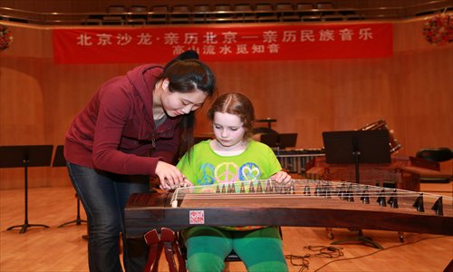 A foreign girl learns the guzheng at a Chinese folk music appreciation event held at the China Conservatory, Chaoyang district Sunday. More than 100 foreigners were invited to the event. Photo: CFP
