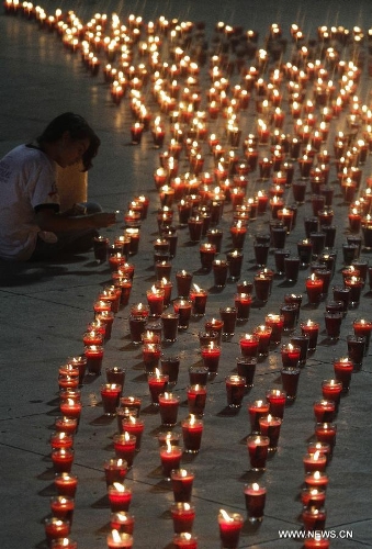  A girl lights candles during a commemoration event for the people that died on consequence of Human Immunodeficiency Virus (HIV), organized by the Atlacatl Association Vivo Positivo, at the Salvador del Mundo Square, in San Salvador, capital of El Salvador, on May 19, 2013. A total of 4,000 candles were lit during the event. (Xinhua/Oscar Rivera) 