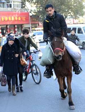 Tang Xinyu, 26, rides his horse in downtown Jinan, Shandong Province Monday. The city is on the young man's route from Beijing to Nanjing. He started his journey on November 6. Photo: CFP