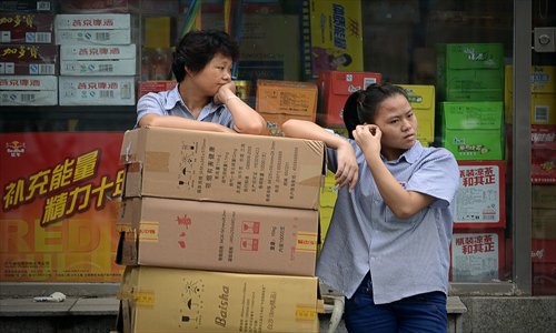 Two Chinese women rest beside goods outside a shop in Beijing on Tuesday. Chinese shares tumbled 3.73 percent this morning, extending the previous day's hefty losses as dealers fret over a liquidity situation in the banking system that has squeezed lenders. Photo: AFP