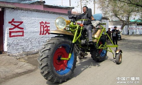 A young Uyghur man goes for a drive through his neighborhood on a giant multicolored homemade motorcycle, which comes in at  4.4 meters long and 2.4 meters high and has a maximum speed of 40 kilometers per hour, in Xinjiang Uygur Autonomous Region, on April 27. Photo:cnr.cn