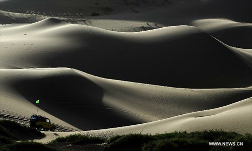 A motorcar runs on the Badain Jaran Desert in Alashan of north China's Inner Mongolia Autonomous Region, June 19, 2012. The Badian Jaran Desert is 47,000 square km and sparsely populated. It is famous for having the tallest stationary sand dunes in the world. Some dunes reach a height of 500 meters. But it also features spring-fed lakes that lie between the dunes. Photo: Xinhua