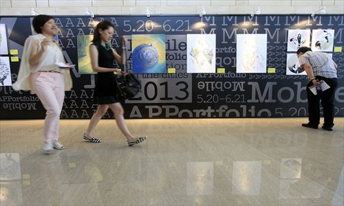 Visitors check out the artwork at a mobile exhibition at Wheelock Square in Jing'an district Wednesday. Each piece was created by a young artist in Asia. The exhibition's slogan this year is 
