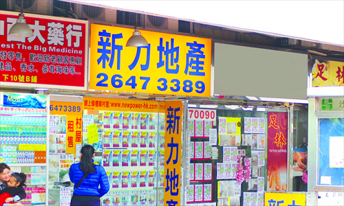 A woman walks past property advertisements posted by real estate agencies in Sha Tin New Town, Hong Kong. Photo: Song Shengxia/GT