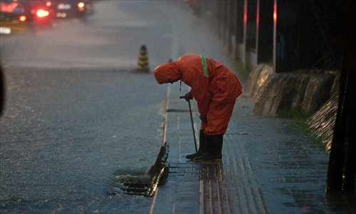 A Beijing flood prevention worker opens a gutter drain grate during a rainstorm last year to ease water on the road. Photo: CFP