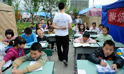 Lushan Middle School students continue classes with volunteers from Southwestern University of Finance and Economics in tents outside their destroyed school. Photo: Li Hao/GT