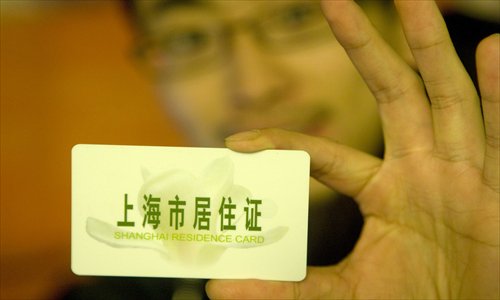 A man displays his Shanghai residence card. For nonlocals, having a residency permit now means their children can attend the same schools as Shanghai children and enjoy many of the same welfare benefits. Photo: CFP