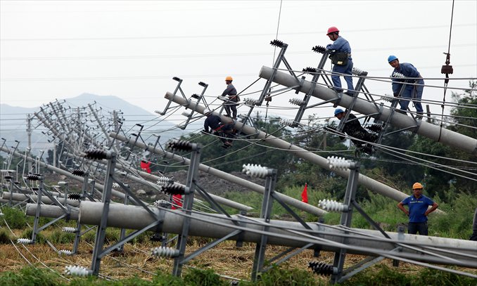 Workers try to fix electric power lines damaged by typhoon Haikui in Wenling, Zhejiang Province Wednesday. Thirty-four power poles were brought down in Songmen town (see also page 3). Photo: CFP