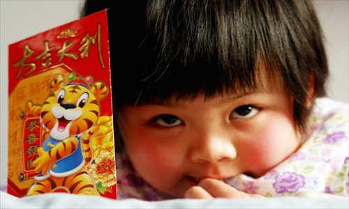 A little girl plays with a red envelope containing money given to her by her parents during Spring Festival in Zhengzhou, Henan Province. Photos: CFP