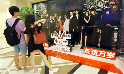 Moviegoers walk past a promotional poster for the film Tiny Times. The film has spurred controversy over its depiction of materialism. Photo: CFP
