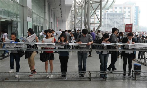 Students read guiding pamphlets while waiting outside a job fair site on October 27, 2012 in Hangzhou, Zhejiang Province. Photo: CFP