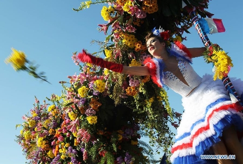 A performer throws flowers to visitors during the flowers parade of the 129th annual Nice Carnival parade, in Nice, southern France, March 2, 2013. (Xinhua/Gao Jing)