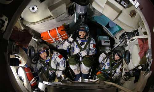Astronauts of China's Shenzhou-10 manned spacecraft Nie Haisheng (C), Zhang Xiaoguang (L) and Wang Yaping (R) who is female are seen in a spaceship simulated reentry capsule April 29, 2013. Photo: Xinhua