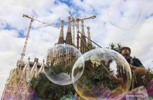 A busker makes soap bubbles in front of the Basilica and Expiatory Church of the Holy Family in Barcelona, Spain, on April 10, 2013. The Roman Catholic church, commonly known as the Sagrada Familia, was designed by Antoni Gaudi (1852-1926) and its construction had commenced in 1882. Although being incomplete after over 130 years, the church is a UNESCO World Heritage Site. (Xinhua/Sun Wen) 