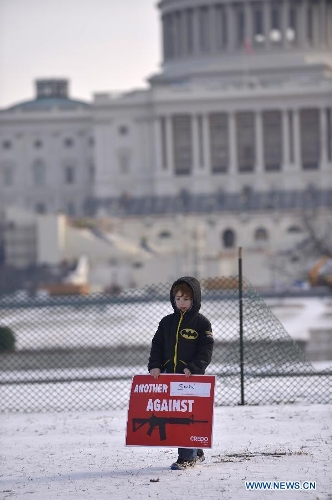 Six-year-old Dylan Wolos holds a sign against gun violence in front of the Capiotl Hill during a march in Washington D.C., capital of the United States, Jan. 26, 2013. Thousands of people, including family members of victims and survivors of shootings at Virginia Tech University, Sandy Hook elementary school and others, took part in a march for stricter gun control laws here on Saturday. (Xinhua/Zhang Jun) 