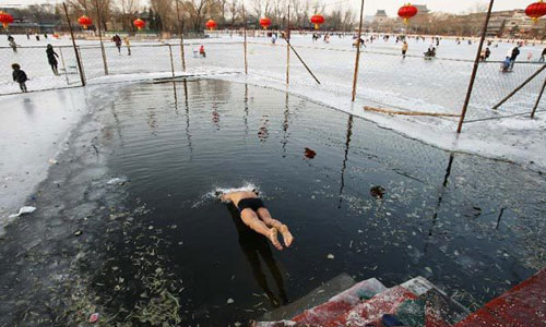 A winter swimmer jumps into the icy water of the frozen Shichahai lake in Beijing, capital of China, December 22, 2012. Temperatures in Beijing could plunge to the lowest in almost three decades over the weekend, weather forecasters said Saturday. Photo: Xinhua