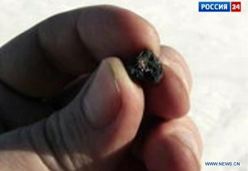 A TV screen grab taken from 24 channel of the Russian State Television shows a scientific researcher holding a meteor fragments found in the chebarkul lake region near Chelyabinsk, about 1500 kilometers east of Moscow, Russia, on Feb. 18, 2013. Scientists have found fragments of a meteor that exploded over Russia's central Urals and triggered a shock wave that injured hundreds and shattered scores of windows, experts said Monday. (Xinhua)  