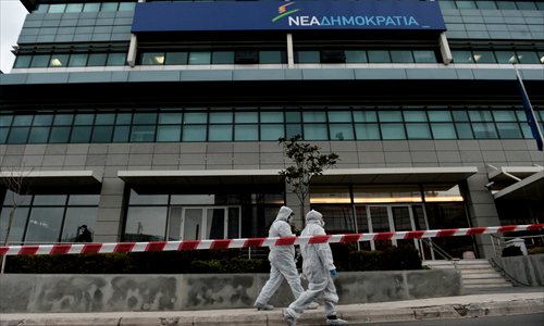 Police investigators walk on Monday outside the headquarters of New Democracy conservative party in Athens. Shots were fired early on Monday near the offices of main Greek ruling party New Democracy in Athens, police said, after a recent wave of arson attacks against political offices. Photo: AFP
