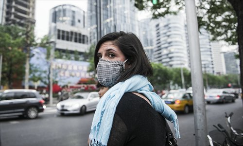 A pedestrian wearing a mask eyes traffic in Sanlitun, Chaoyang district, earlier this month. Beijing’s expat labor market has remained competitive, despite lingering concerns it could suffer due to foreign workers leaving China. Photo: Li Hao/GT