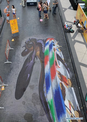 Pedstrians look at street paintings in Bangkok, Thailand, March 2, 2013. One local artist and 19 others from over the world feast the eyes of Thai people with their 3D and 4D street paintings during the Living Arts Festival held in Bangkok. (Xinhua/Gao Jianjun) 