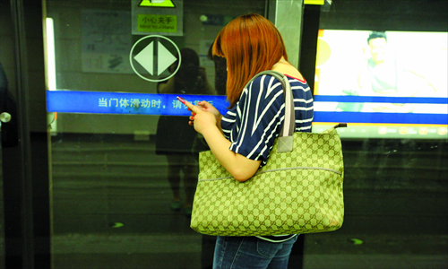 Above: A passenger carrying a branded handbag waits for her subway train. Photo: Guo Yingguang/GT