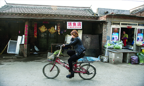 A woman cycles past a shop run by the family of an H7N9-infected boy on Monday in Naidong village, Chaoyang district. Photo: Li Hao/GT