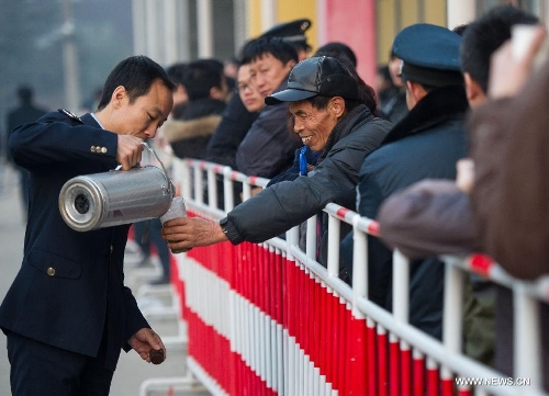 A staff member of taxation bureau sends hot water to people who have stayed up all night long for standing in a line at 7 a.m. outside the Sixth Taxation Office of Chaoyang District Local Taxation Bureau in Beijing, capital of China, March 8, 2013. Secondhand housing transaction surges in Beijing these days as buyers and sellers are rushing to 