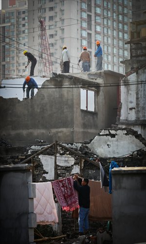 One of the remaining residents in the neighborhood airs his quilts in the remains of a home. Photo: Cai Xianmin/GT