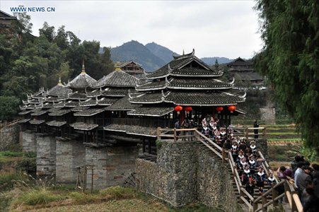 People of the Dong ethnic group walk through the Chengyang Fengyu Bridge in Sanjiang Dong Autonomous county, Southwest China's Guangxi Zhuang Autonomous Region, December 1, 2012. A celebration ceremony was held on Saturday to mark the 100th anniversary of the completion of Chengyang Fengshui Bridge. Built in 1912, the 77.76-meter-long bridge is famed for its combination of bridge, veranda and Chinese pavilion. (Xinhua/Wu Lianxun) 