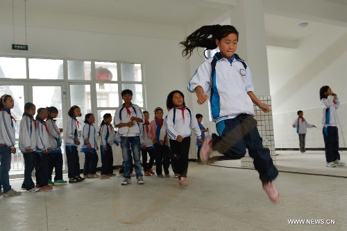 Students of the central primary school of Shangli Town play rope-skipping in a makeshift classroom in Shangli, Lushan County, southwest China's Sichuan Province, May 16, 2013. The schoolhouses of the Shangli Town Center School were destroyed in the 7.0-magnitude earthquake taken place in Lushan on April 20, leaving more than 1, 200 students to have classes in newly built prefab houses. (Xinhua/Liu Xiao)&nbsp; 