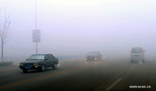 Cars run on a street in dense fog in Baoding, north China's Hebei Province, Jan. 12, 2013. Heavy fog enveloped several regions in east and central China Saturday, causing highway closures and flight delays in several provinces. (Xinhua/Wang Xiao)