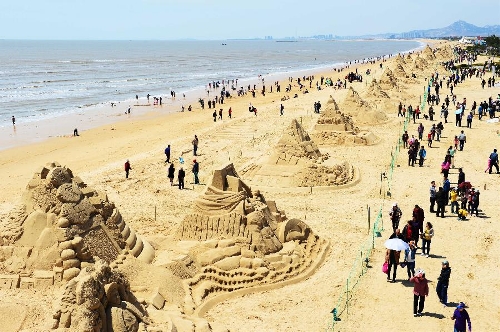 People walk past sand sculptures along the beach in Nanhai New District in Wendeng City, east China's Shandong Province, April 29, 2013. The 2,500-meter-long sand sculpture group attracted many tourists on Monday, the first day of the three-day Labor Day holiday. (Xinhua/Guo Xulei) 
