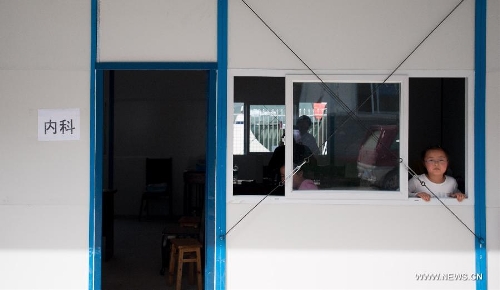 A child looks out of a window of a temporarily-erected prefabricated house at the People's Hospital in Lushan County, southwest China's Sichuan Province, May 12, 2013. Eight prefabricated houses have been built here to provide medical services to residents. The county was jolted by a 7.0-magnitude earthquake on April 20. (Xinhua/Li Hualiang) 