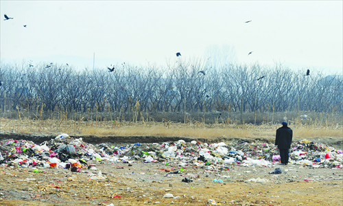 A man stands amid the piles of trash at a dumping site near Bingmaying village, Miyun county. Environmentalists claim it may pollute the nearby Miyun Reservoir. Photo: CFP