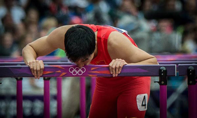 China's Liu Xiang kisses a hurdle after men's 110m hurdles heat at London 2012 Olympic Games, London, Britain, Aug. 7, 2012. Liu Xiang tumbled and was disqualified for semifinal. Photo: Xinhua