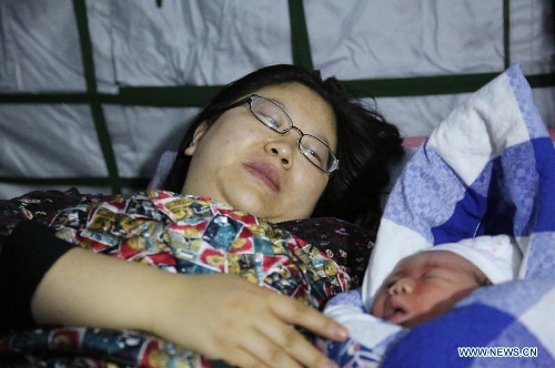 Zhang Jing and her newborn baby girl rest in a tent functioned as an operating room of the People's Hospital in Baoxing County, Ya'an City, southwest China's Sichuan Province, April 21, 2013. The girl was the first baby born in the hospital after the earthquake. A 7.0-magnitude earthquake jolted Lushan County of Ya'an City on Saturday morning. (Xinhua/Zhang Yuanpei) 