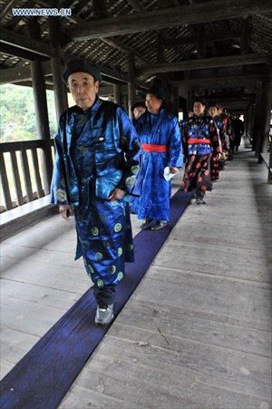 People of the Dong ethnic group walk through the Chengyang Fengyu Bridge during a celebration ceremony marking the 100th anniversary of its completion held in Sanjiang Dong Autonomous county, South China's Guangxi Zhuang Autonomous Region, December 1, 2012. Built in 1912, the 77.76-meter-long bridge is famed for its combination of bridge, veranda and Chinese pavilion. (Xinhua/Liang Kechuan) 
