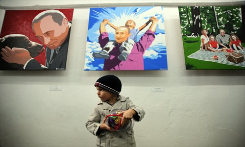 A boy stands in front of the paintings by artist Alexei Sergiyenko at his exhibition 