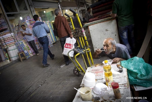 An Iranian worker eats his lunch at Tehran's old main bazaar in downtown Tehran, Iran, on May 20, 2013. Economic condition of Iranian families is the core issue of the hopeful candidates for Iran's 11th presidential election, as the inflation rate of the Islamic republic, according to the Iranian Statistics Center, reached 29.8 percent in the first month of the current Iranian calendar year (March 21-April 20). (Xinhua/Ahmad Halabisaz) 