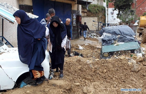 Local residents pass vehicles stuck in mud in Beni Messous suburb, in upper Algiers, Algeria, on May 22, 2013. Heavy rain poured since Tuesday in several provinces in northern part of the country, claiming the life of one citizen, injuring three others, and causing extensive damages. (Xinhua/Mohamed Kadri) 