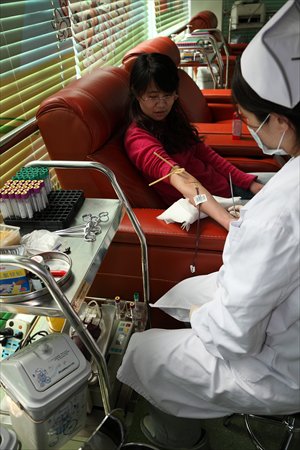 A resident donates her blood at a blood collection station in Beijing. A donor usually gives out 400 millimeters of blood each time, and receive a certificate with a red cover in which the amount and date of the donation are recorded. Photo: CFP
