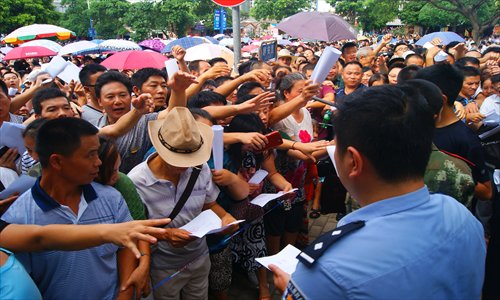 Police officers distribute notices to a crowd of people queuing up outside a branch of the People's Bank of China, who mistakenly believed they could get an interest-free loan in Beihai, Guangxi Zhuang Autonomous Region, on Tuesday.  Photo: IC