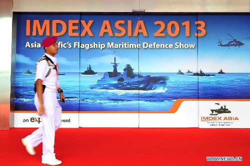A member of Singapore armed forces walks past an exhibition billboard during the International Maritime Defense Exhibition (IMDEX) Asia at Changi Exhibition Centre in Singapore, May 14, 2013. The three-day exhibition started here on Tuesday. (Xinhua/Then Chih Wey)