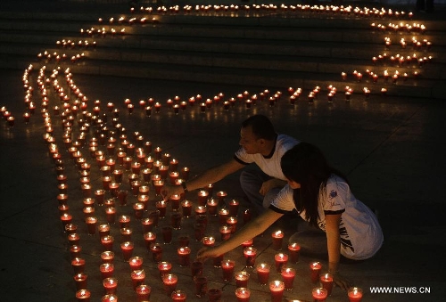  People light candles during a commemoration event for the people that died on consequence of Human Immunodeficiency Virus (HIV), organized by the Atlacatl Association Vivo Positivo, at the Salvador del Mundo Square, in San Salvador, capital of El Salvador, on May 19, 2013. A total of 4,000 candles were lit during the event. (Xinhua/Oscar Rivera) 