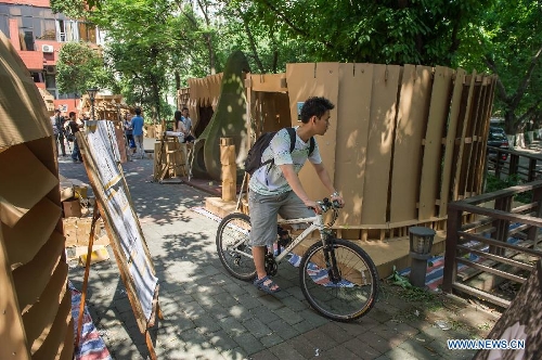 People visit paper houses in the Chongqing University, Chongqing, southwest China, May 21, 2013. Fourteen paper houses, made up with recycled paper by more than 200 freshmen, were displayed in the Faculty of Architecture and Urban Planning of the university on Tuesday. (Xinhua/Chen Cheng) 