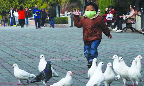 A mask-wearing child approaches pigeons in Shanghai’s People’s Square on April 6. Photo: Cai Xianmin/GT