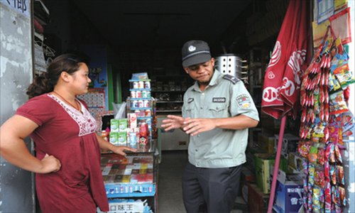 A foreign chengguan volunteer talks to a local shopowner.

