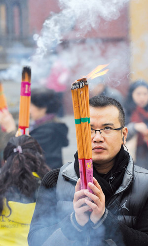 A man burns incense at the Pilu Temple in Nanjing, Jiangsu Province on January 1, 2012. Photo: CFP
