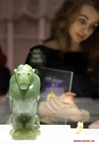 A visitor looks at a jade lion presented on the exhibition of 