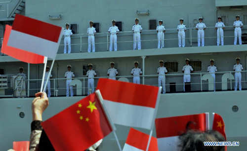 People wave flags to welcome the arrival of the Chinese Navy training vessel 